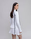 Woman wearing a white outfit with black accents on a gray background
