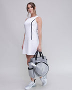 Woman holding a sports bag with a white dress and sneakers on a gray background