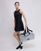Woman holding a gray duffel bag with a logo on a white background