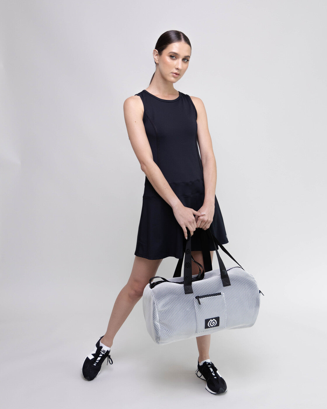Woman holding a white duffel bag with a black background