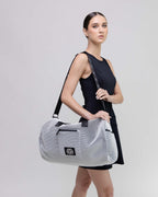 Woman holding a white mesh duffel bag with a brand logo on a light gray background
