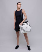 Woman holding a white and black handbag against a gray background