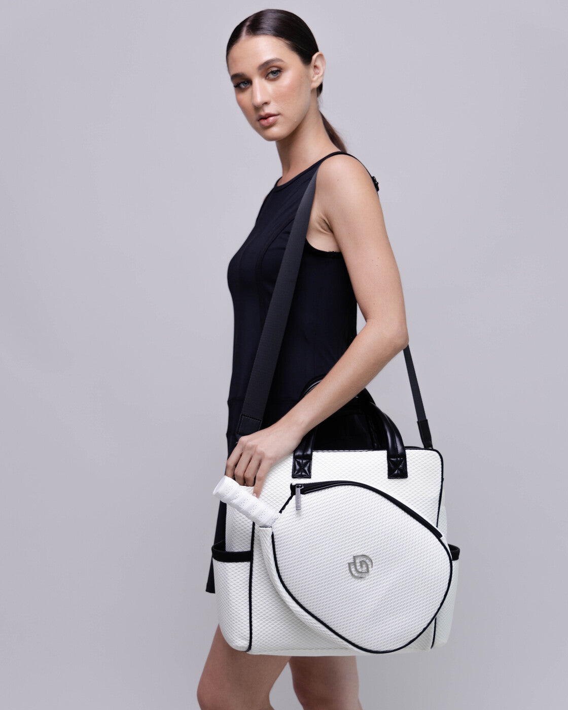 Woman holding a white handbag with black accents on a gray background