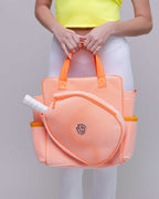 Person holding an orange mesh bag with a white handle against a gray background