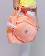 Person holding an orange mesh bag with a logo on a plain background