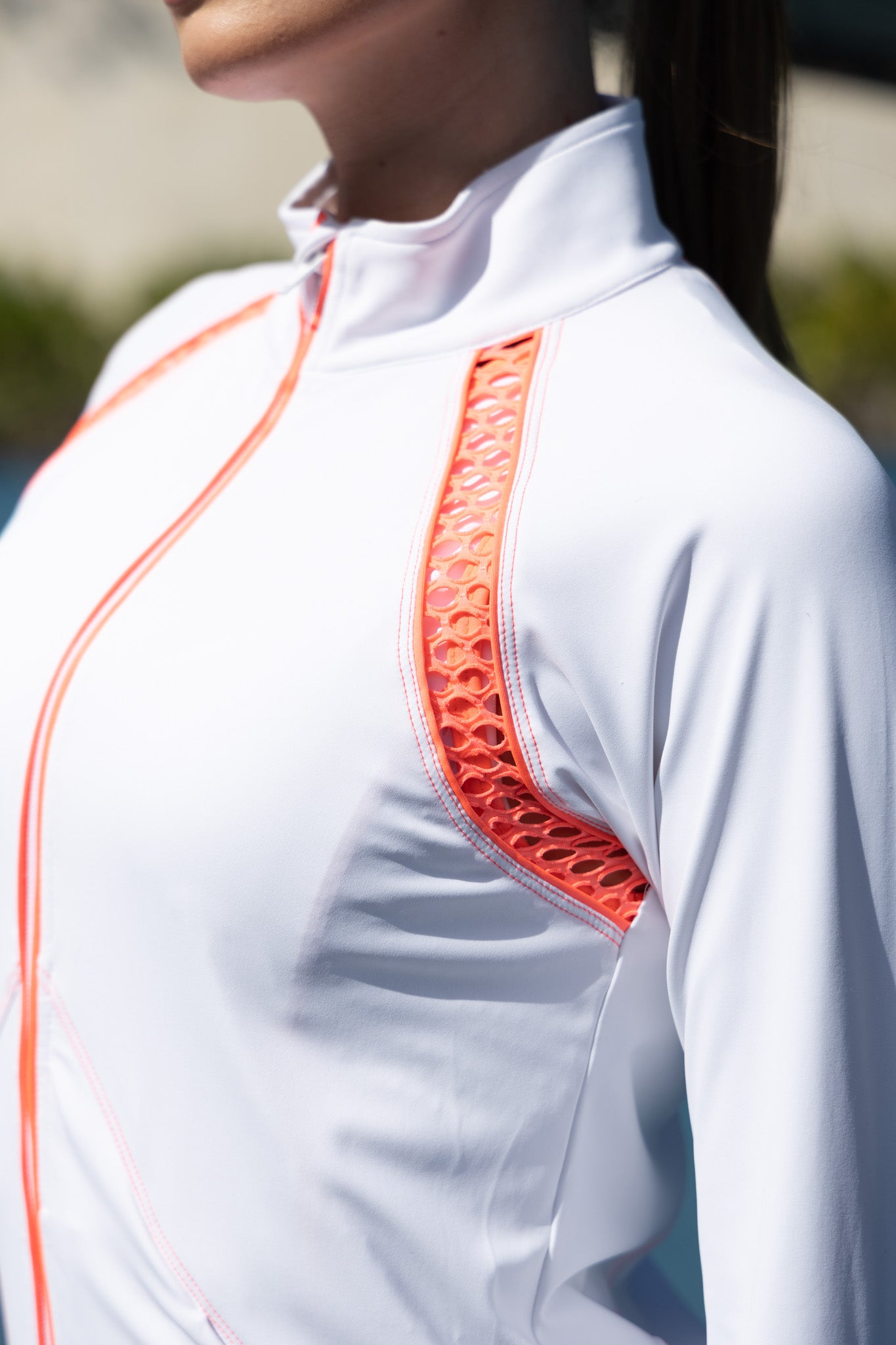 Close-up of a white shirt with orange accents worn by a person.