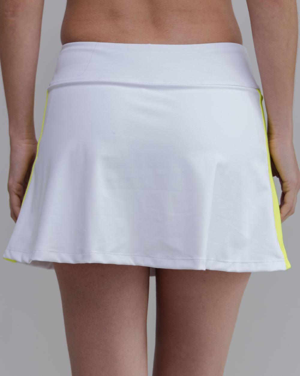 White tennis skirt with yellow trim on a gray background