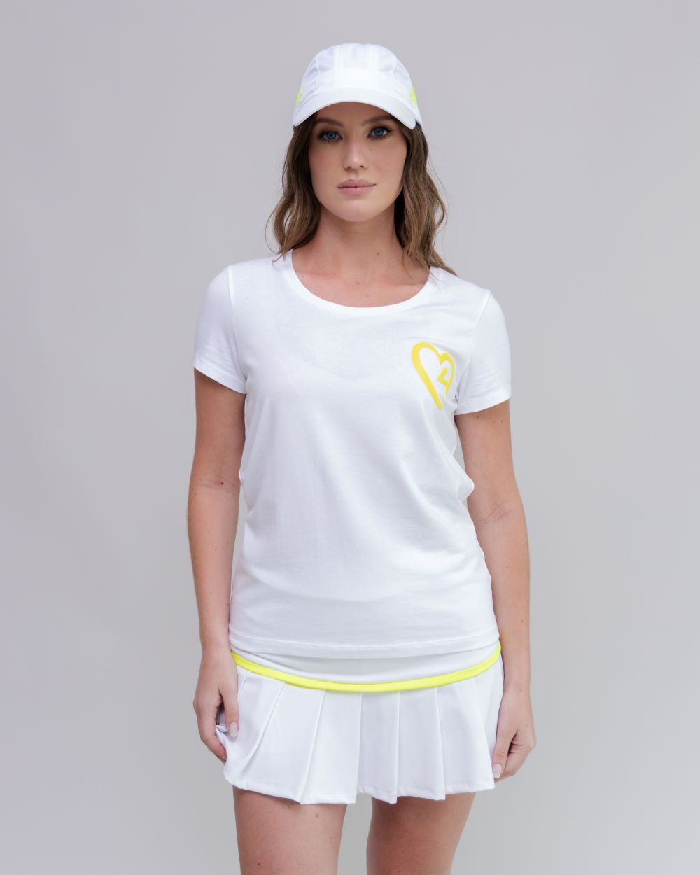 Woman wearing a white tennis outfit with a yellow logo on a gray background