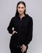 Woman wearing a black hoodie against a plain background