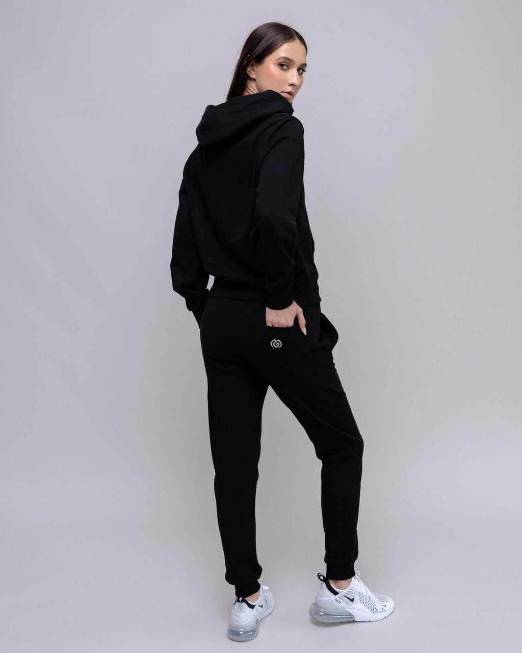 Person wearing a black tracksuit with a plain background