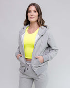 Woman wearing a gray tracksuit with a yellow top on a light gray background