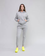 Woman wearing a gray tracksuit with yellow shoes on a plain background