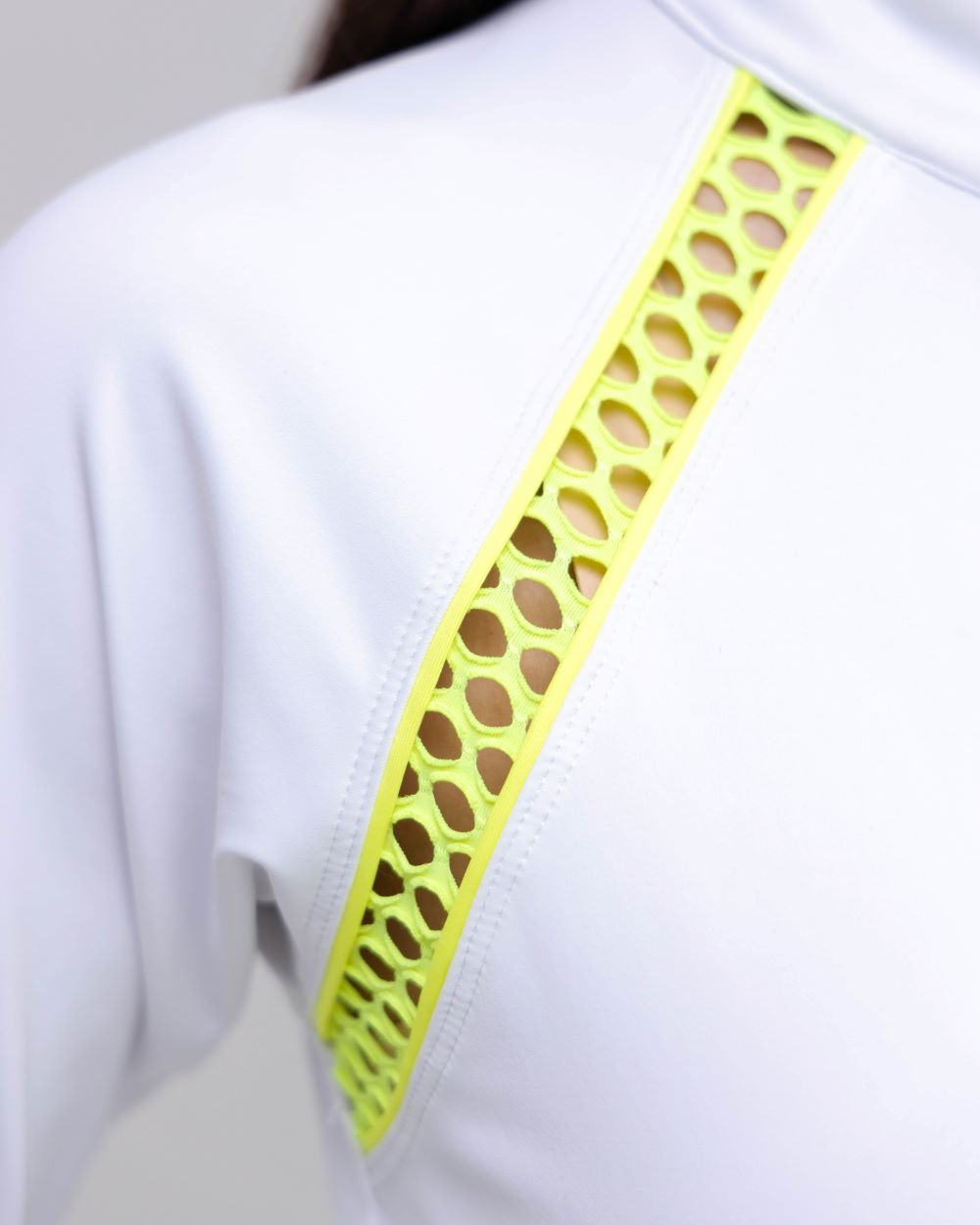 Close-up of a white shirt with a green perforated strip on a plain background