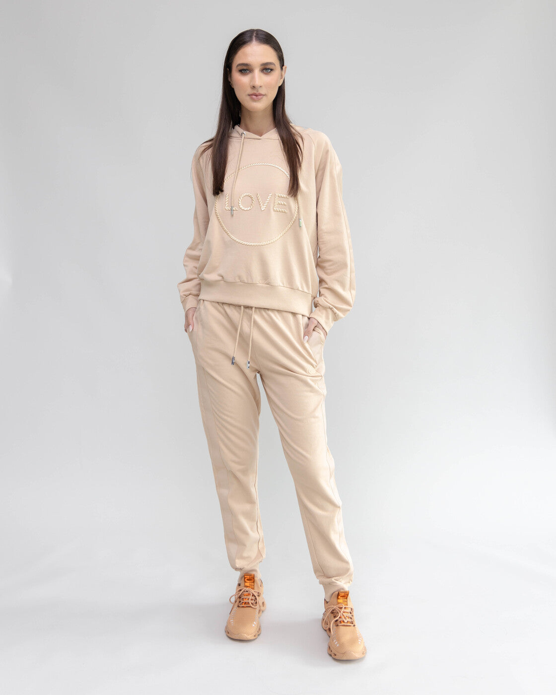 Woman wearing a beige tracksuit with 'LOVE' text on a white background