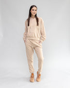 Woman wearing a beige tracksuit with 'LOVE' printed on the hoodie against a light gray background