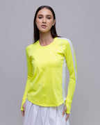 Woman wearing a bright yellow long-sleeve top with white accents on a gray background