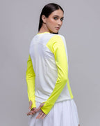 Woman wearing a white and yellow long-sleeve top on a gray background