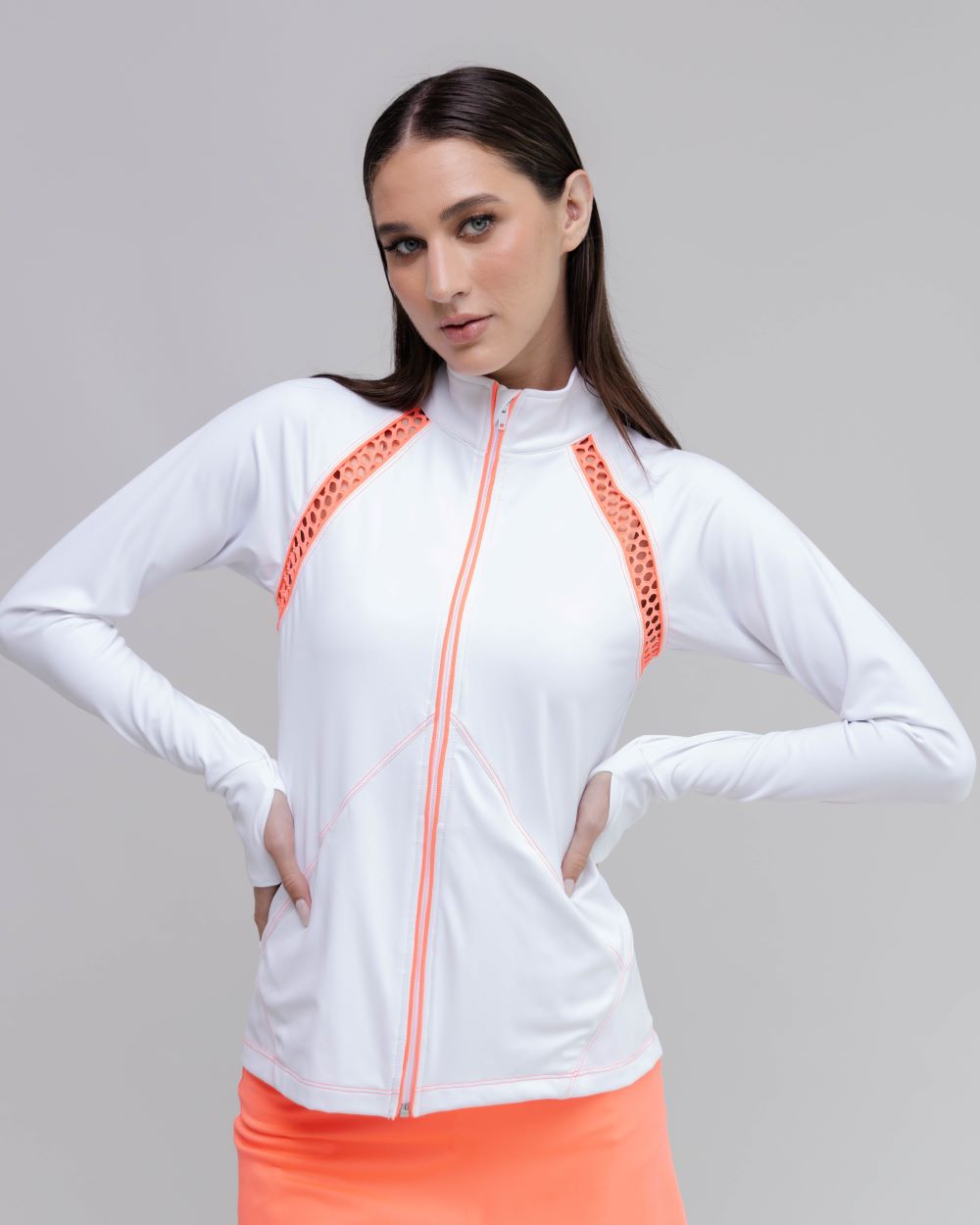 Woman wearing a white jacket with orange accents on a gray background