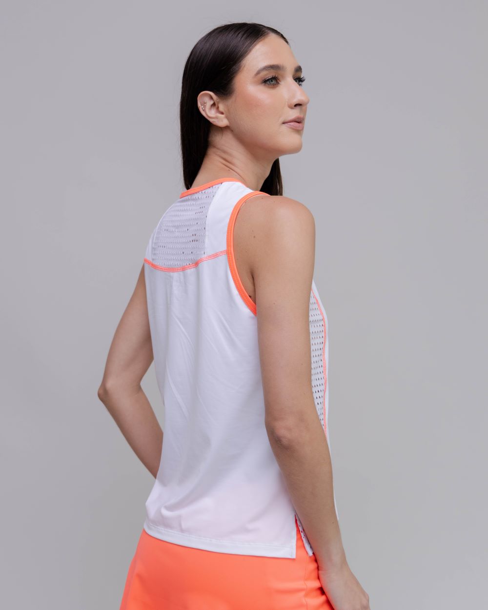 Woman wearing a white tank top with orange accents on a gray background