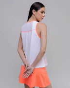 Woman wearing a white sleeveless top with pink accents and an orange skirt on a gray background