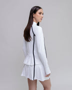 Woman wearing a white outfit with black accents on a gray background