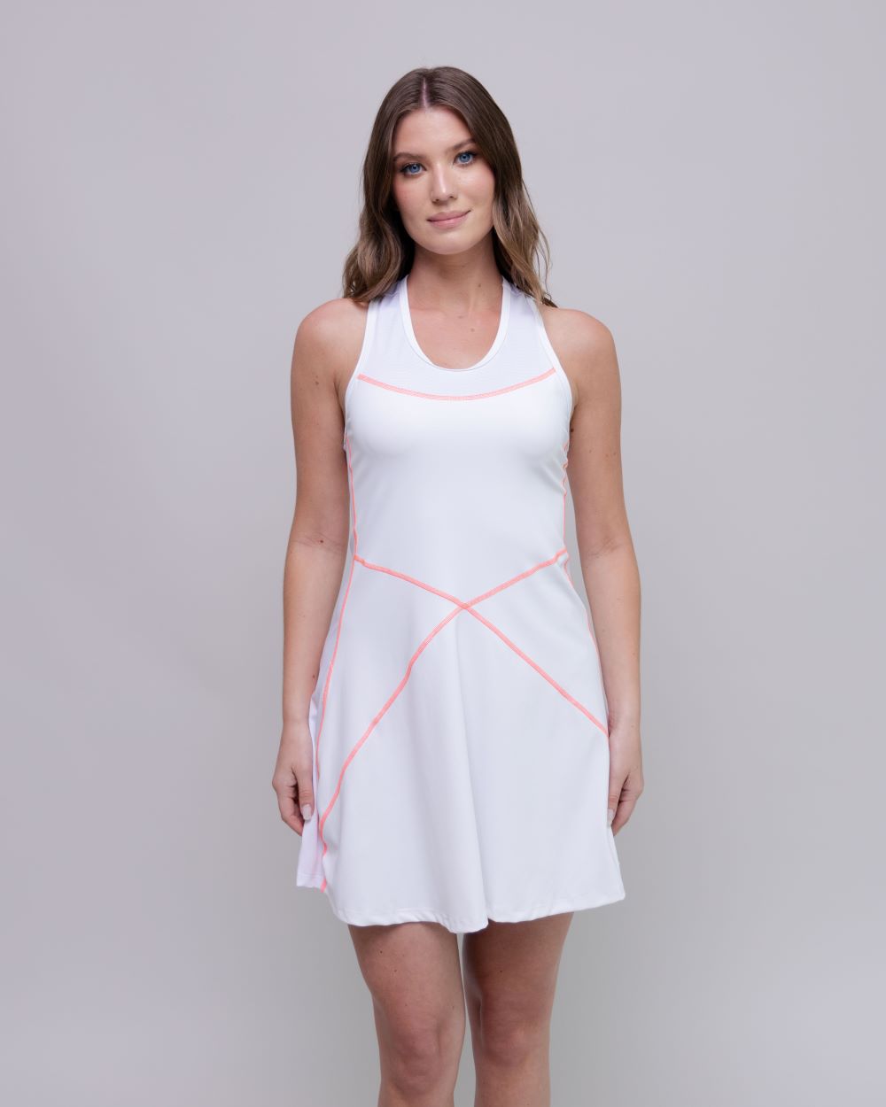 Woman wearing a white dress with pink accents on a gray background