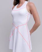 White dress with pink accents worn by a person on a plain background