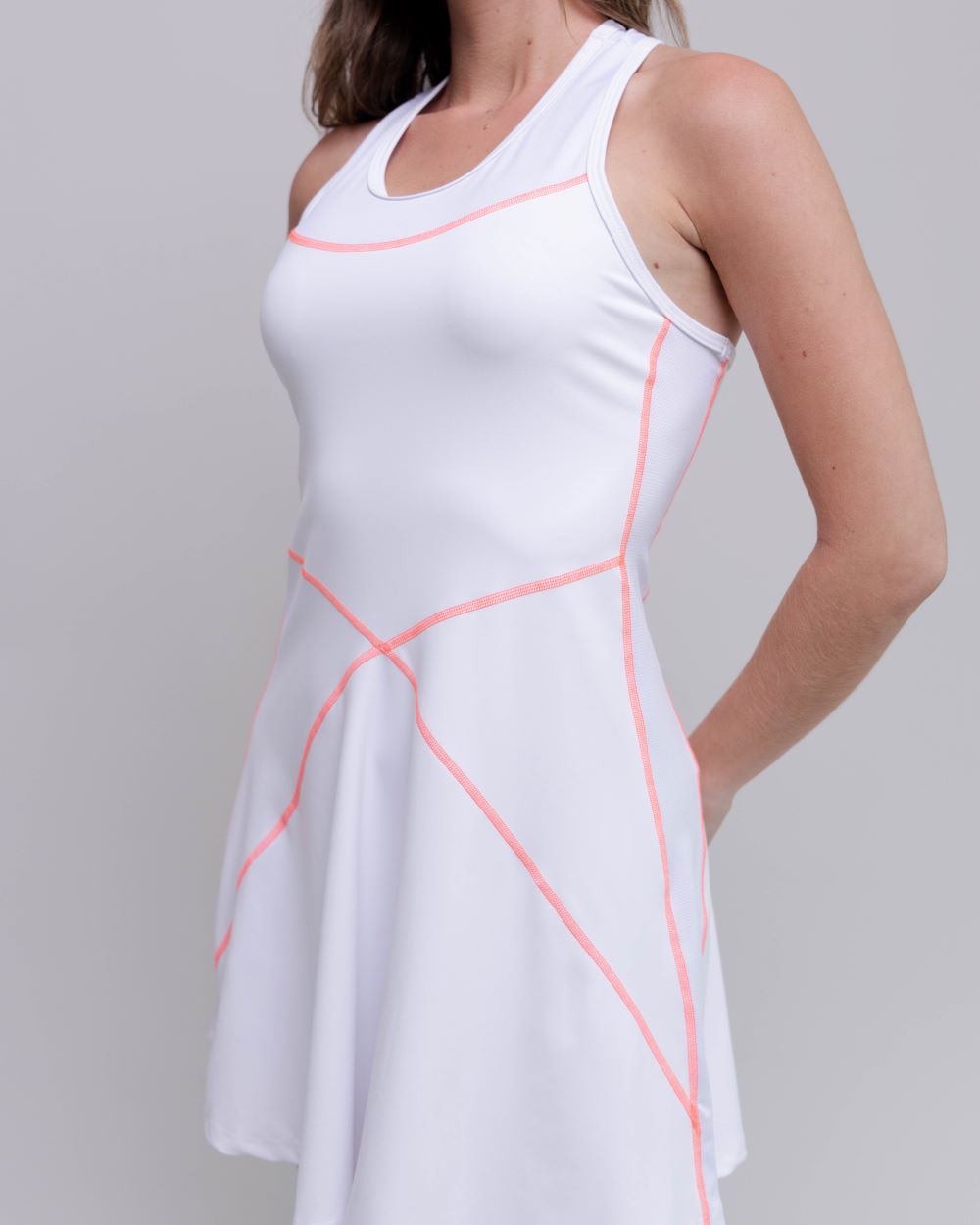 White dress with pink accents worn by a person on a plain background