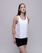 Woman wearing a white tank top with black trim and black shorts on a gray background