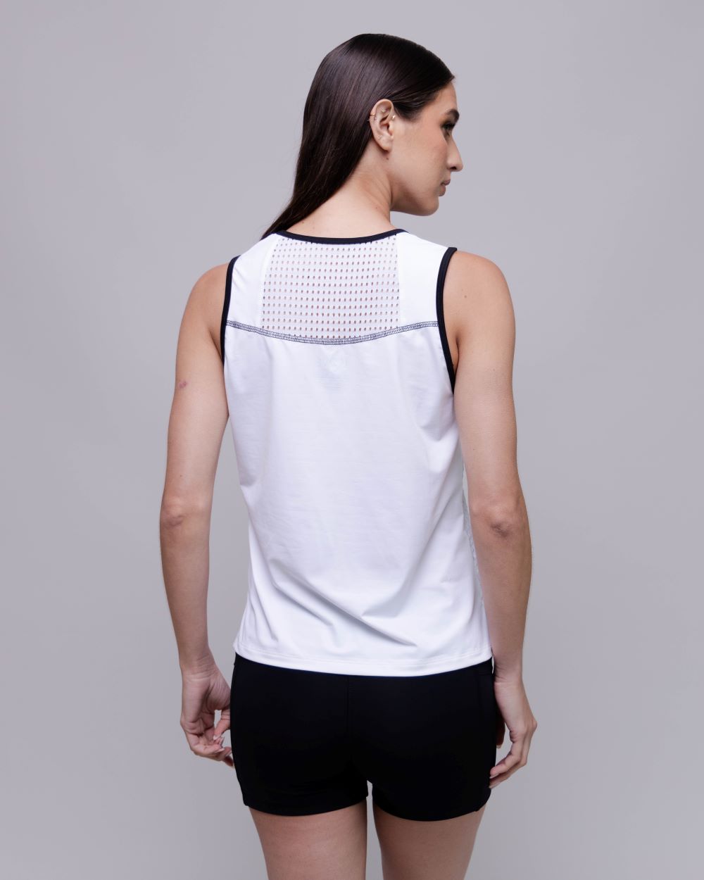 Woman wearing a white sleeveless top with black accents on a gray background