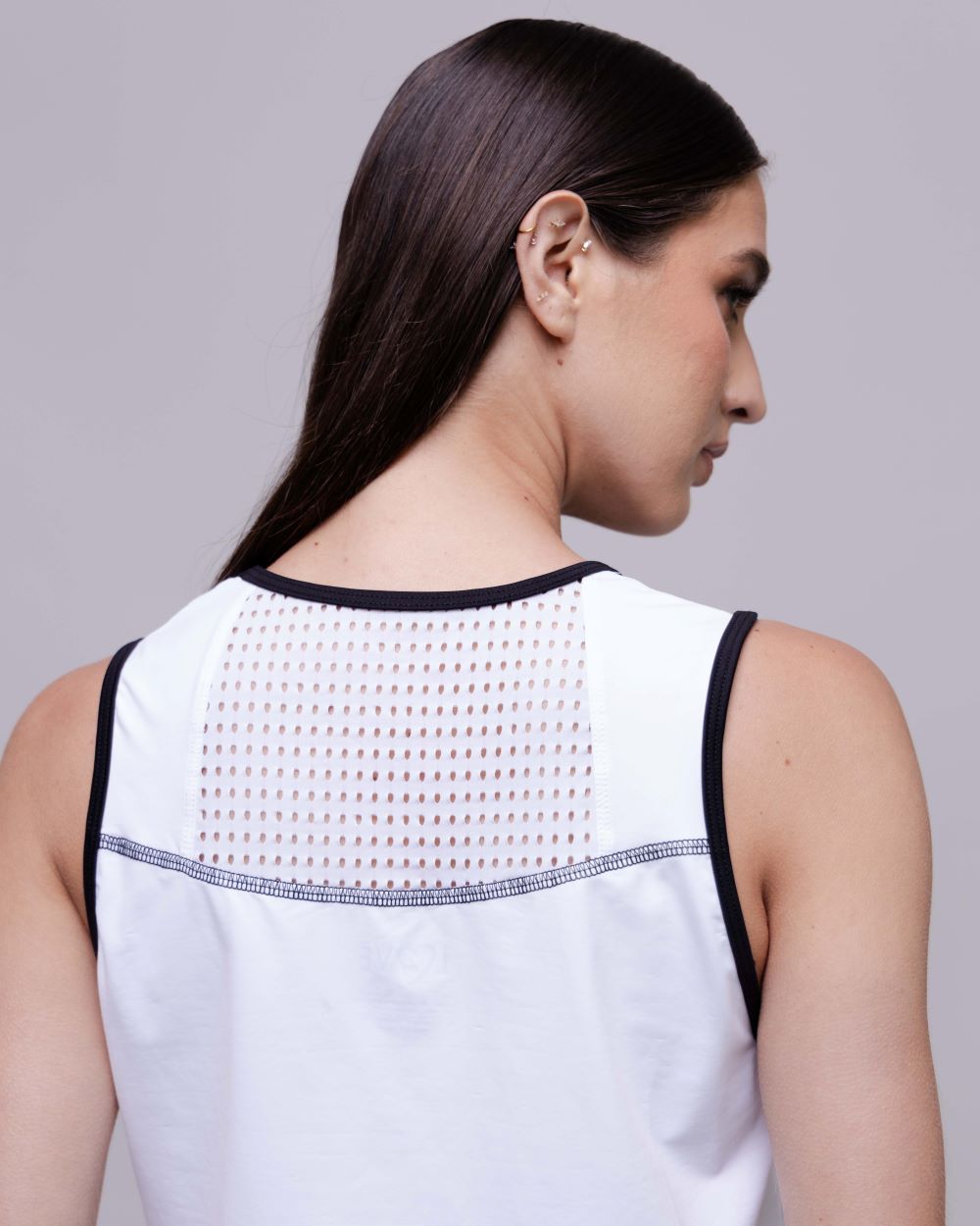 Woman wearing a sleeveless top with a textured back design on a gray background