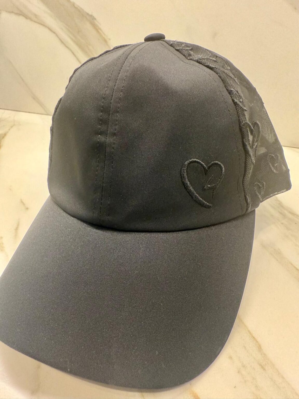 Black cap with a heart design on a beige background Main image