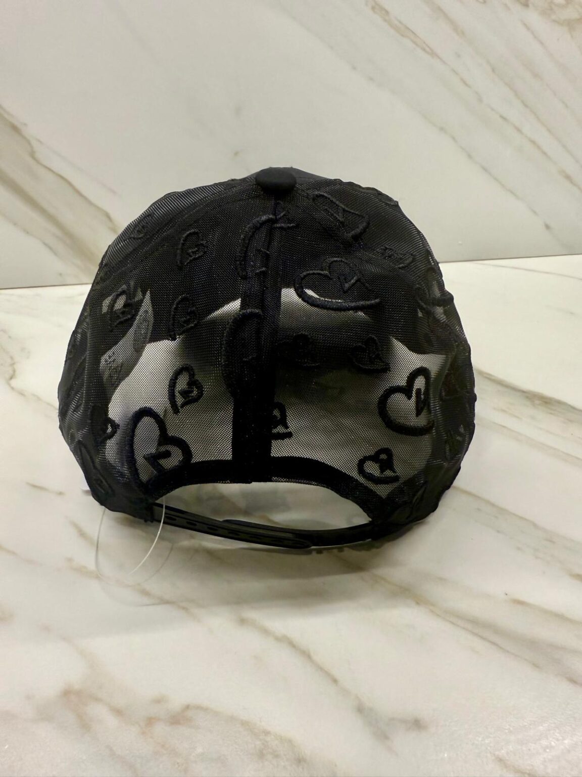 Black cap with heart patterns on a marble surface